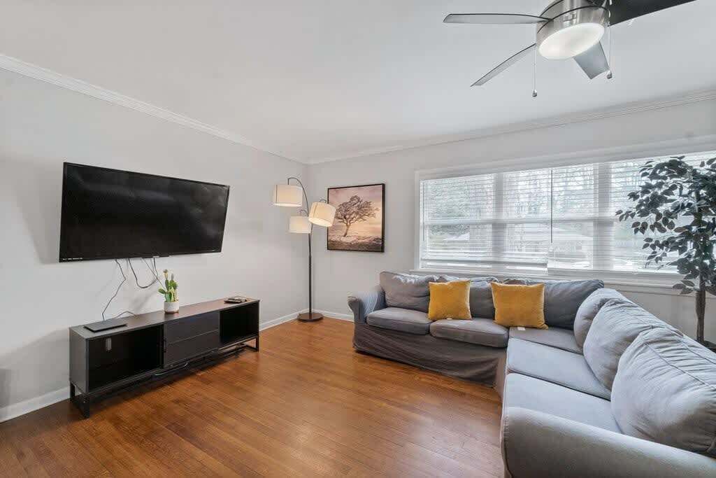 Een moderne woonkamer met een flatscreen televisie, een vloerlamp, een bank en een plafondventilator.