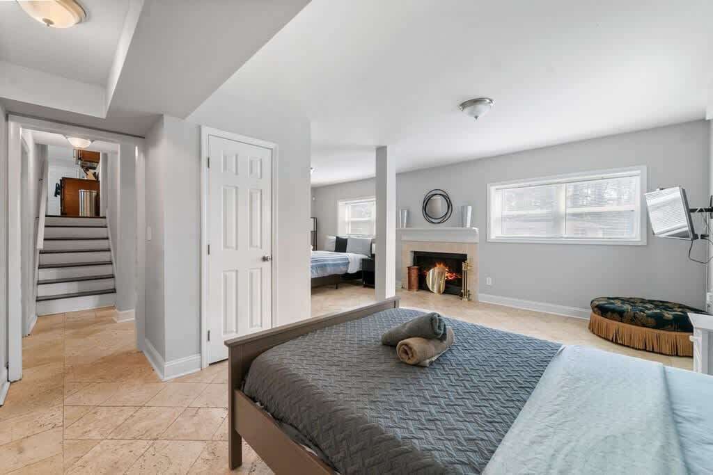 A bedroom with a bed, a fireplace, a window, and a staircase leading to another room.