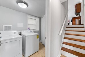 A laundry room with two washing machines, a dryer, and a window with blinds. - Pool retreat near Atlanta, sleeps 14 (Decatur)