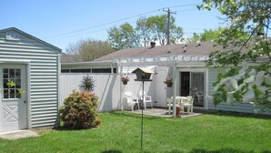A small, single-story house with a fenced backyard, a patio with outdoor furniture, and a small garden area. - In-town Lewes location is near shops, museums, parks, bay and ocean beaches. (Lewes)
