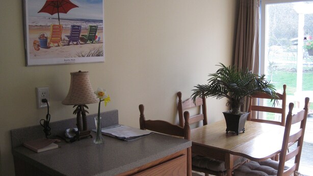 A dining area with a table, chairs, a lamp, a vase with flowers, and a beach-themed painting on the wall. - In-town Lewes location is near shops, museums, parks, bay and ocean beaches. (Lewes)
