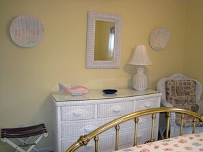 Cozy retreat with a golden headboard bed, dresser, and patterned chair.