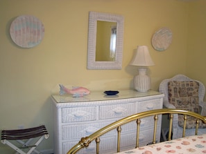 Cozy retreat with a golden headboard bed, dresser, and patterned chair.