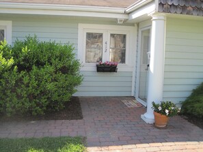 Stunning home with a beautifully manicured front yard, featuring a brick pathway and a charming window box with flowers.