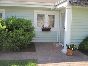 Stunning home with a beautifully manicured front yard, featuring a brick pathway and a charming window box with flowers.