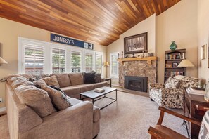 Ein gemütliches Wohnzimmer mit Kamin aus Stein, einer Sofagarnitur und einem Bücherregal.