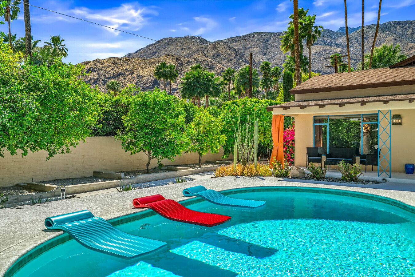 A swimming pool with lounge chairs, a pergola, and a mountain backdrop.