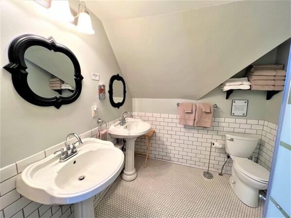 Un baño con dos lavamanos, un inodoro y un espejo.