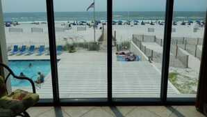 A view of a beach with a pool, lounge chairs, and umbrellas. - Seabatical at The Gulf Tower, Beautiful Beachfront Condo (Gulf Shores)