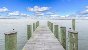Une jetée en bois s’étendant sur une étendue d’eau calme, sous un ciel dégagé.