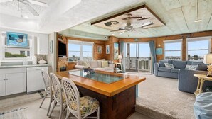 Un vaste espace de vie doté d’un plafond en bois, d’un îlot central et offrant une vue sur l’extérieur.