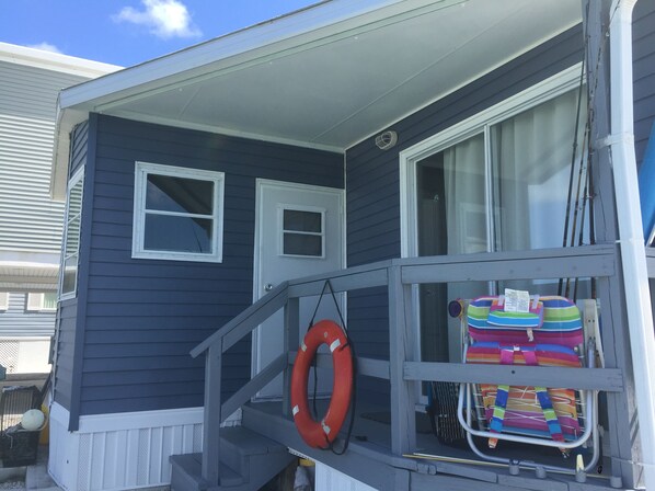 Une maison avec une véranda, une bouée de sauvetage et des chaises de plage colorées.