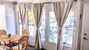 A dining area with a table and chairs, a ceiling fan, and large windows with curtains. - Relax by Florida Keys Beaches, just a 7-min drive away (Cudjoe Key)