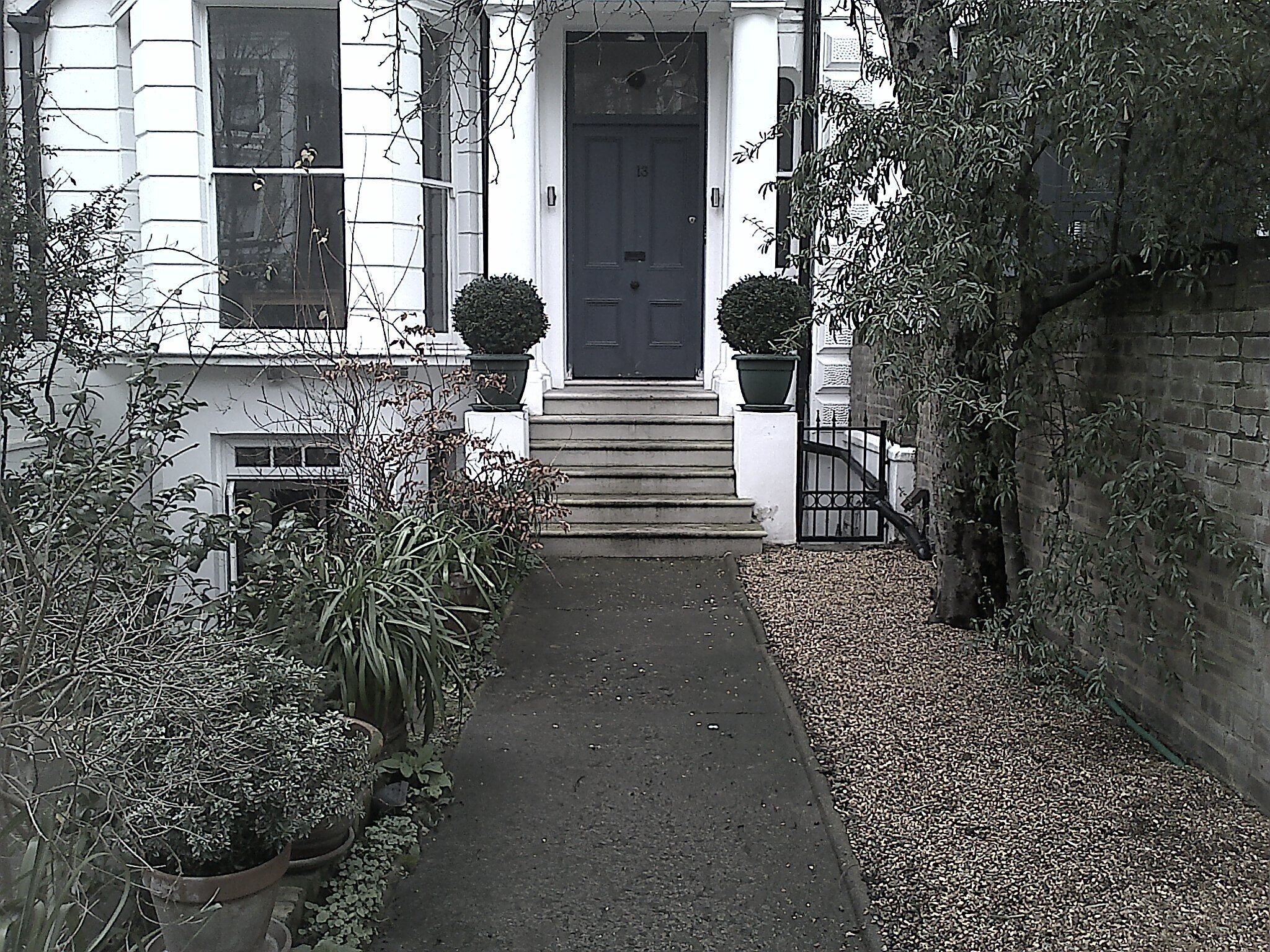 Approaching the front door with the apartment bay window to the left.