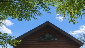 Une cabane en bois avec une véranda, deux chaises et une petite fenêtre.