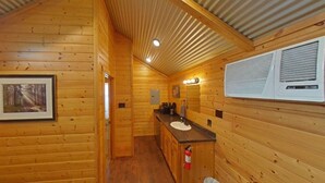 L’intérieur d’une cabane en bois, avec un tableau encadré, un évier et un extincteur.