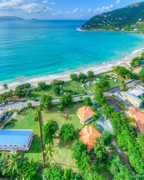 Una proprietà costiera con spiaggia, prati verdi e diversi edifici con tetti rossi.