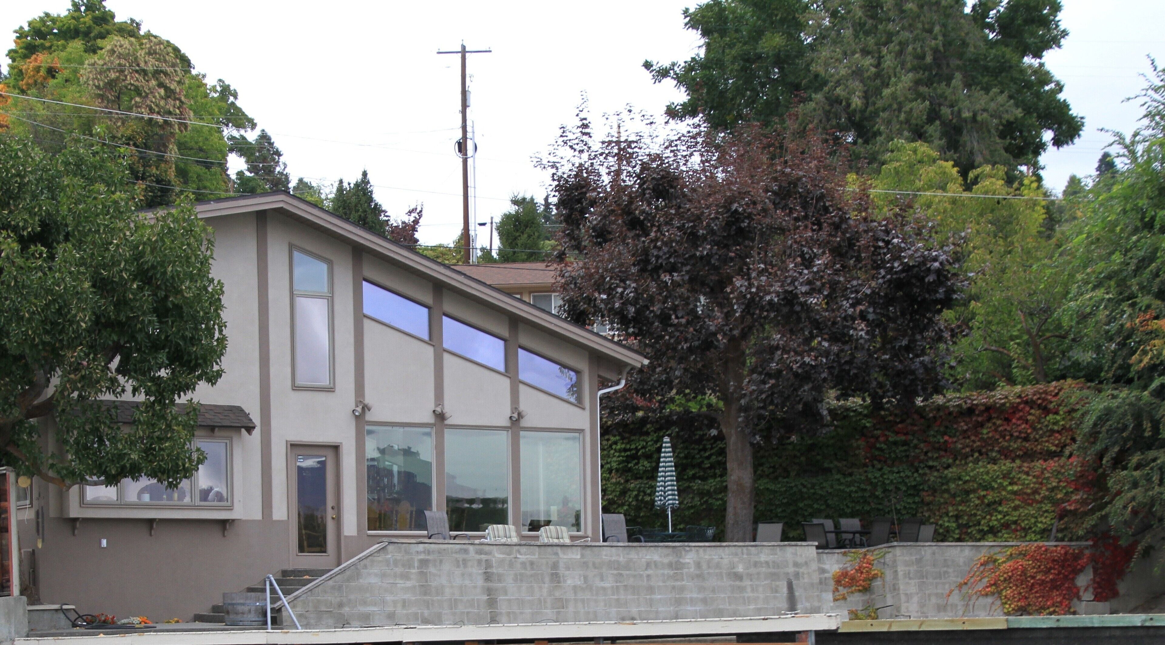 Une maison moderne à deux étages, dotée de grandes fenêtres et d’un balcon.