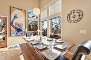 Un espace repas moderne avec une longue table en bois, de nombreuses chaises et un grand tableau abstrait accroché au mur.