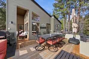 Une maison moderne dotée d’une terrasse, d’un espace salon extérieur et d’un coin barbecue.