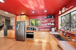 Une cuisine moderne avec des meubles en bois, des appareils électroménagers en acier inoxydable et un mur d’accent rouge.