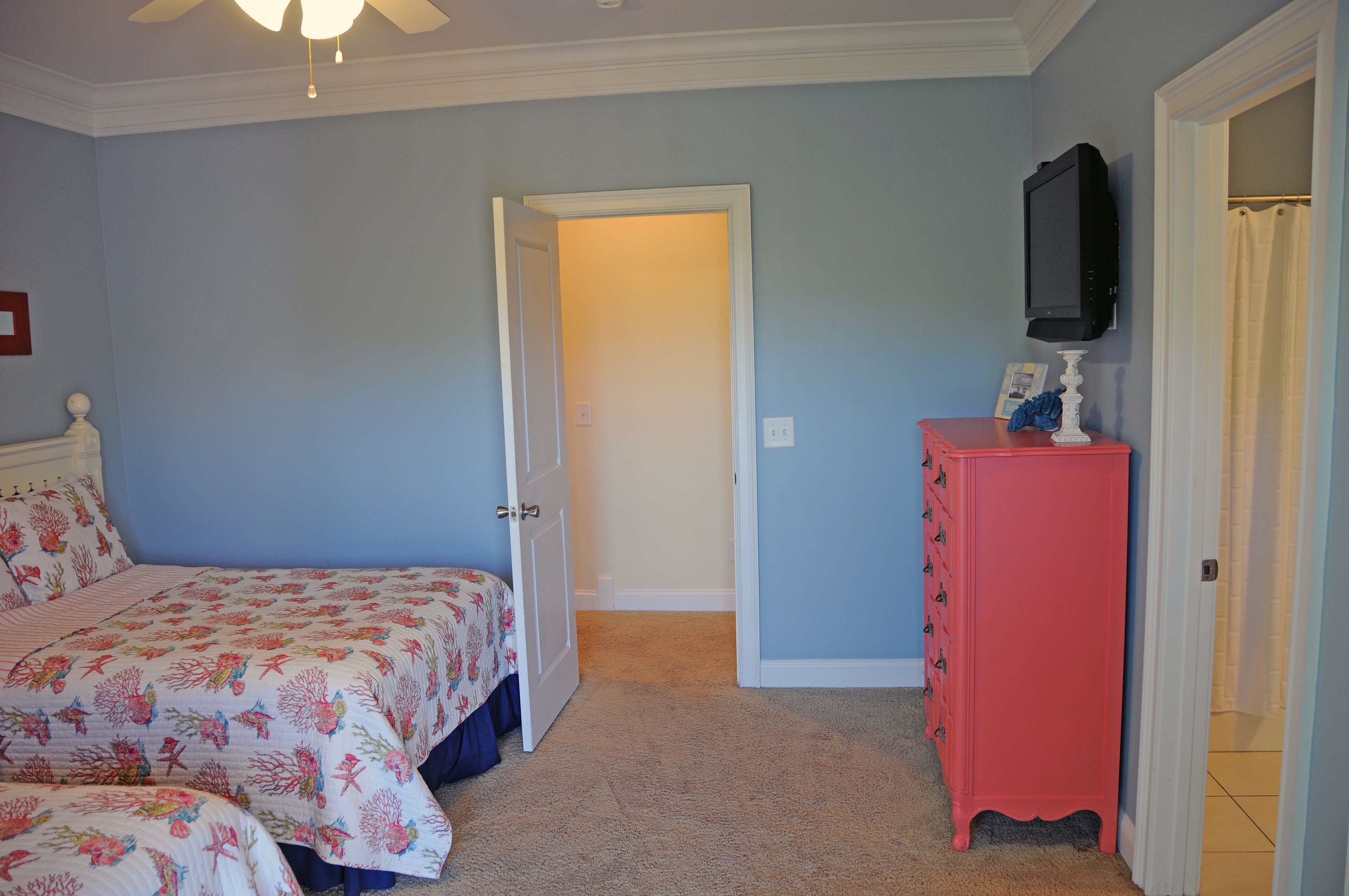 Une chambre à coucher avec un lit, une commode et un téléviseur fixé au mur.