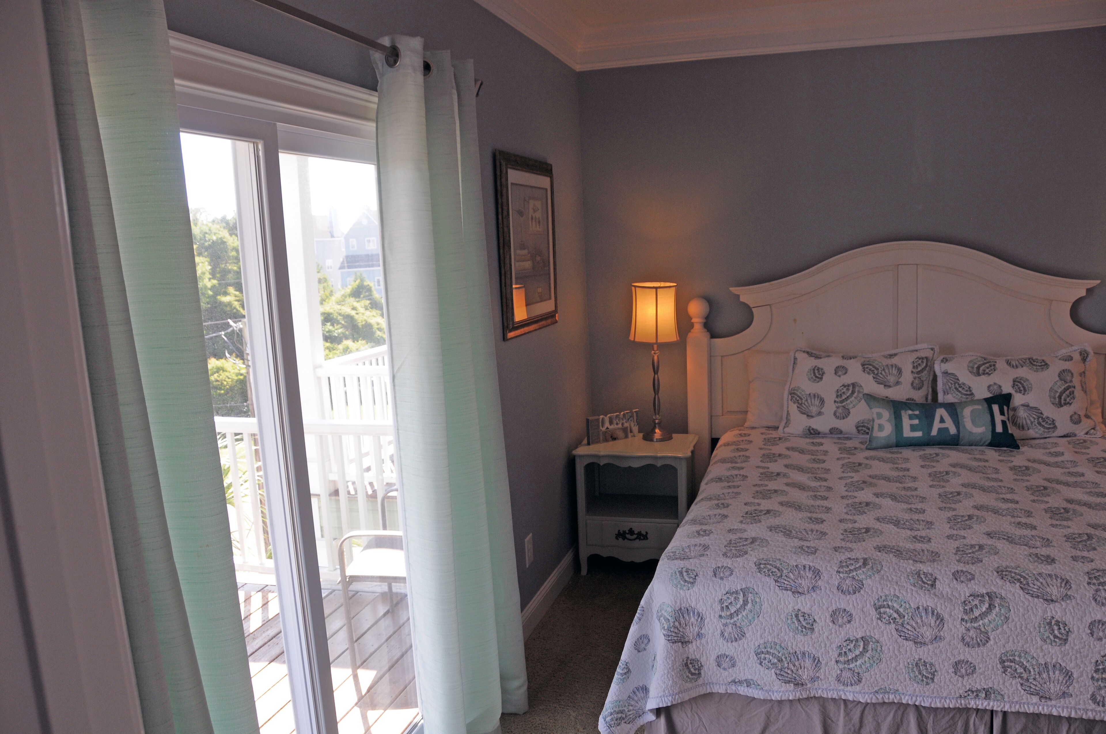 A bedroom with a bed, a nightstand, a lamp, and a window with curtains.