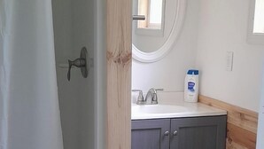 Een badkamer met een douche, toilet en wastafel.