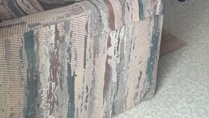 Een stapelbed met een geruit dekbed, een houten nachtkastje met een lamp en een gestreept bankje.