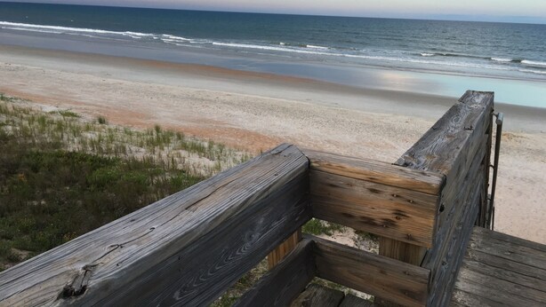 Un muelle de madera que conduce a una playa, con vista al océano.