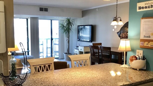 A kitchen with granite countertops, wooden cabinets, and a dining area with a table and chairs. - Ocean Front, North Ocean City, Maryland  (Ocean City)