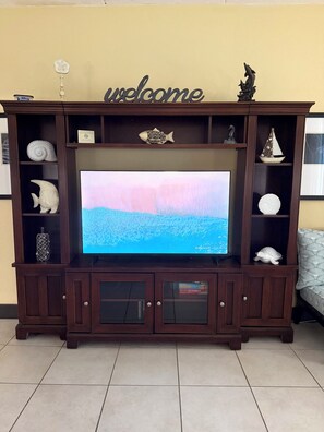 Un mueble de madera con centro de entretenimiento, televisor de pantalla plana, adornos y un letrero que dice 'welcome'.