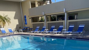 A swimming pool with blue lounge chairs and a pool ladder.