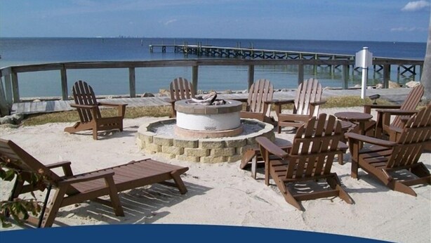 A beachside seating area with Adirondack chairs and a fire pit, overlooking the ocean.