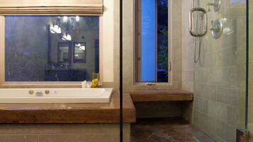 Un baño moderno con bañera, ducha y un ventanal grande.