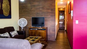 Ein modernes Wohnzimmer mit Flachbildfernseher, einer Couch, einem Couchtisch und einem Ventilator.