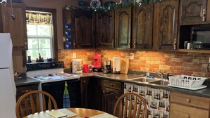 A kitchen with wooden cabinets, a stove, a sink, and a dining table with chairs.