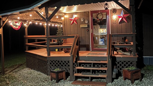 A wooden cabin with a porch, outdoor seating, and string lights.