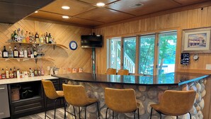 Zona bar con parete in pietra, soffitto in legno e televisore a parete.