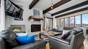 A modern living room with leather sofas, a fireplace, and large windows. - Northview Blue Mountain (blue mountains)