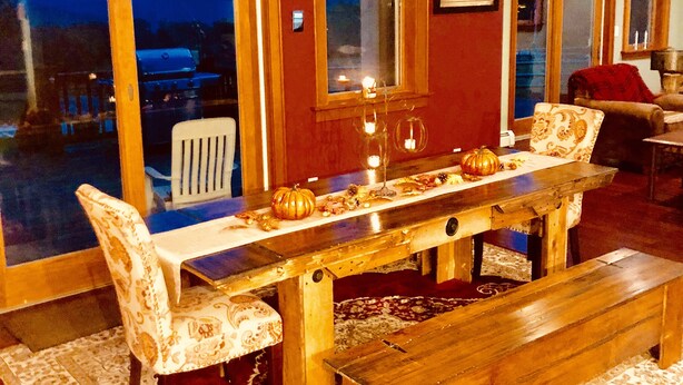 A dining area with a wooden table, patterned chairs, and a bench. - Luxury Mountain Home with Hot Tub, Sauna & Views — Walk to Mountain Top Inn (Chittenden)