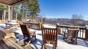 A wooden deck with snow-covered furniture and a view of mountains. - Luxury Mountain Home with Hot Tub, Sauna & Views — Walk to Mountain Top Inn (Chittenden)