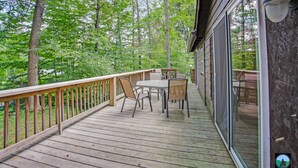 Eine Holzterrasse mit Tisch und Stühlen, umgeben von Bäumen.