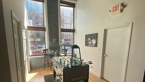 Une pièce avec une table de baby-foot, un lustre et un panneau de signalisation indiquant la sortie.