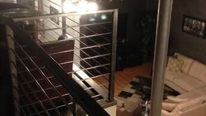 Une pièce avec un escalier, un canapé blanc et une rambarde en métal.