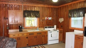 Une cuisine de taille réduite, dotée de meubles de rangement en bois, d’une cuisinière, d’un évier et d’un réfrigérateur.