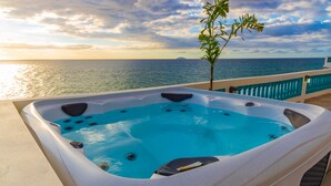 Un jacuzzi con vistas al océano al atardecer.