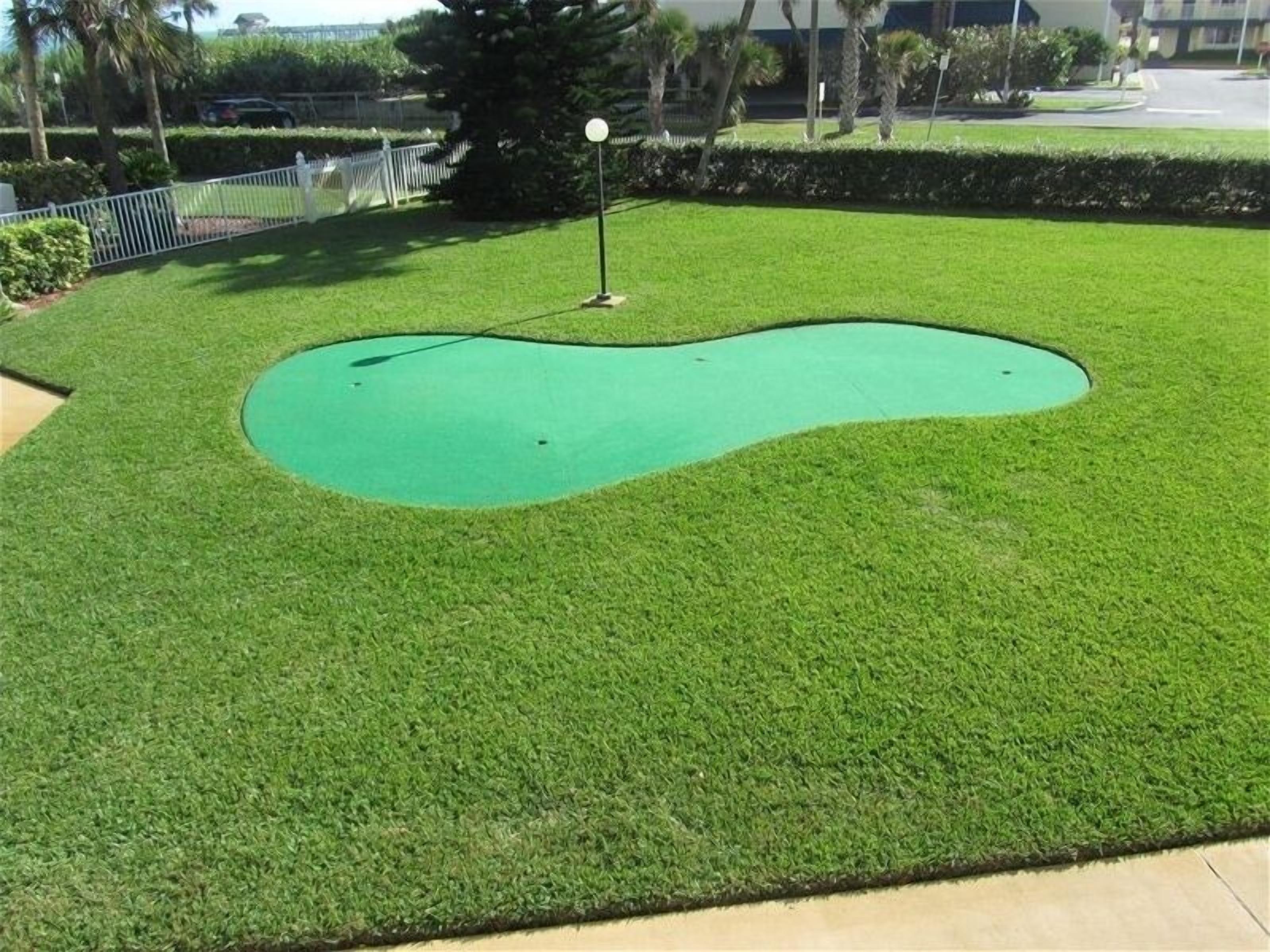 Een goed onderhouden midgetgolfbaan met een groen oefen oppervlak en een vlag.