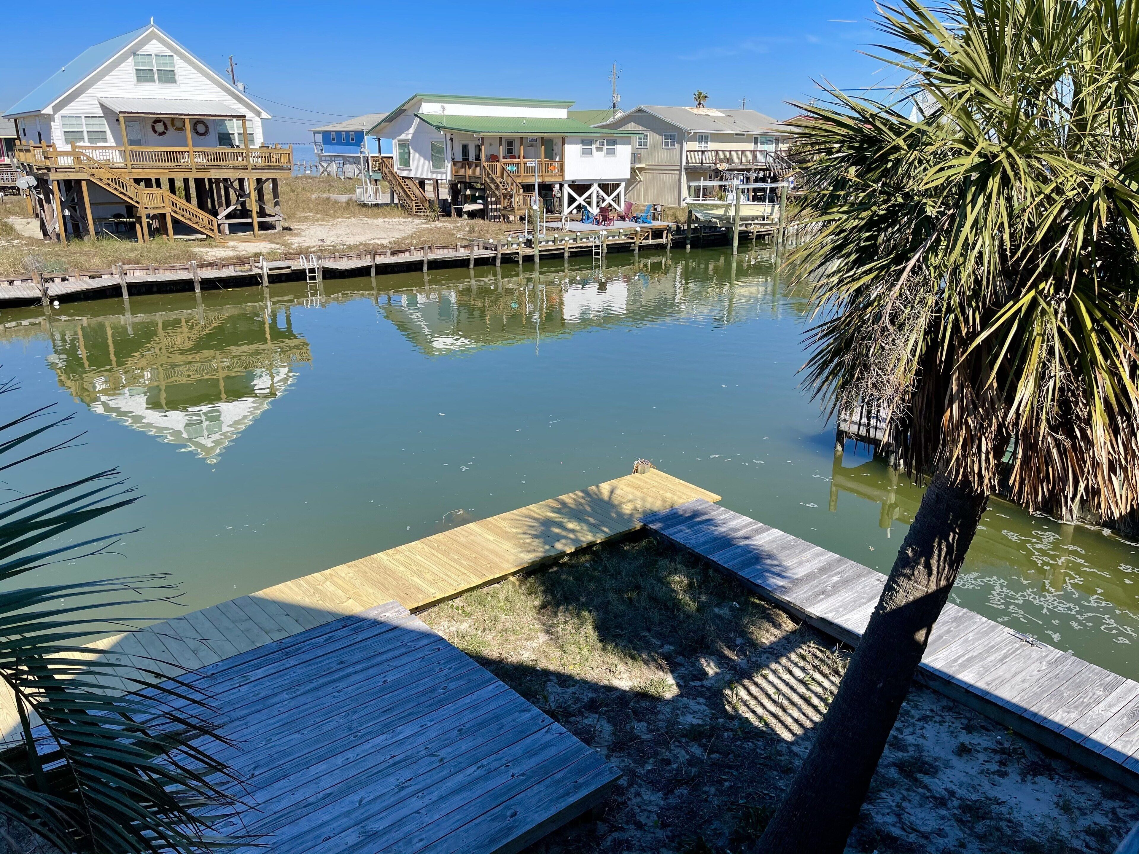 A waterfront property with a dock, a small boat, and a house with a green roof.