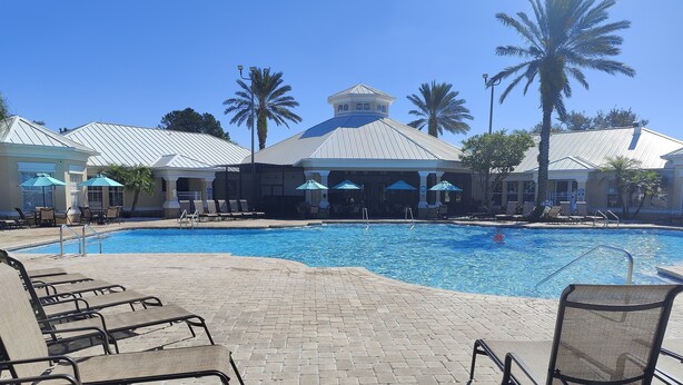 A pool area with lounge chairs, a swimming pool, and palm trees. - 
Orlando Dreams Come True – Private Splash Pool, 3 En-Suite BRs, Near Disney (Kissimmee)